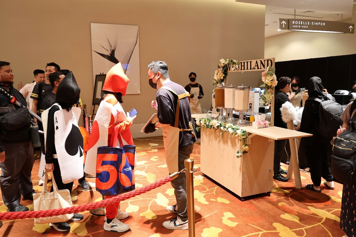 A group of people in costumes queue in front of a drinks stand.