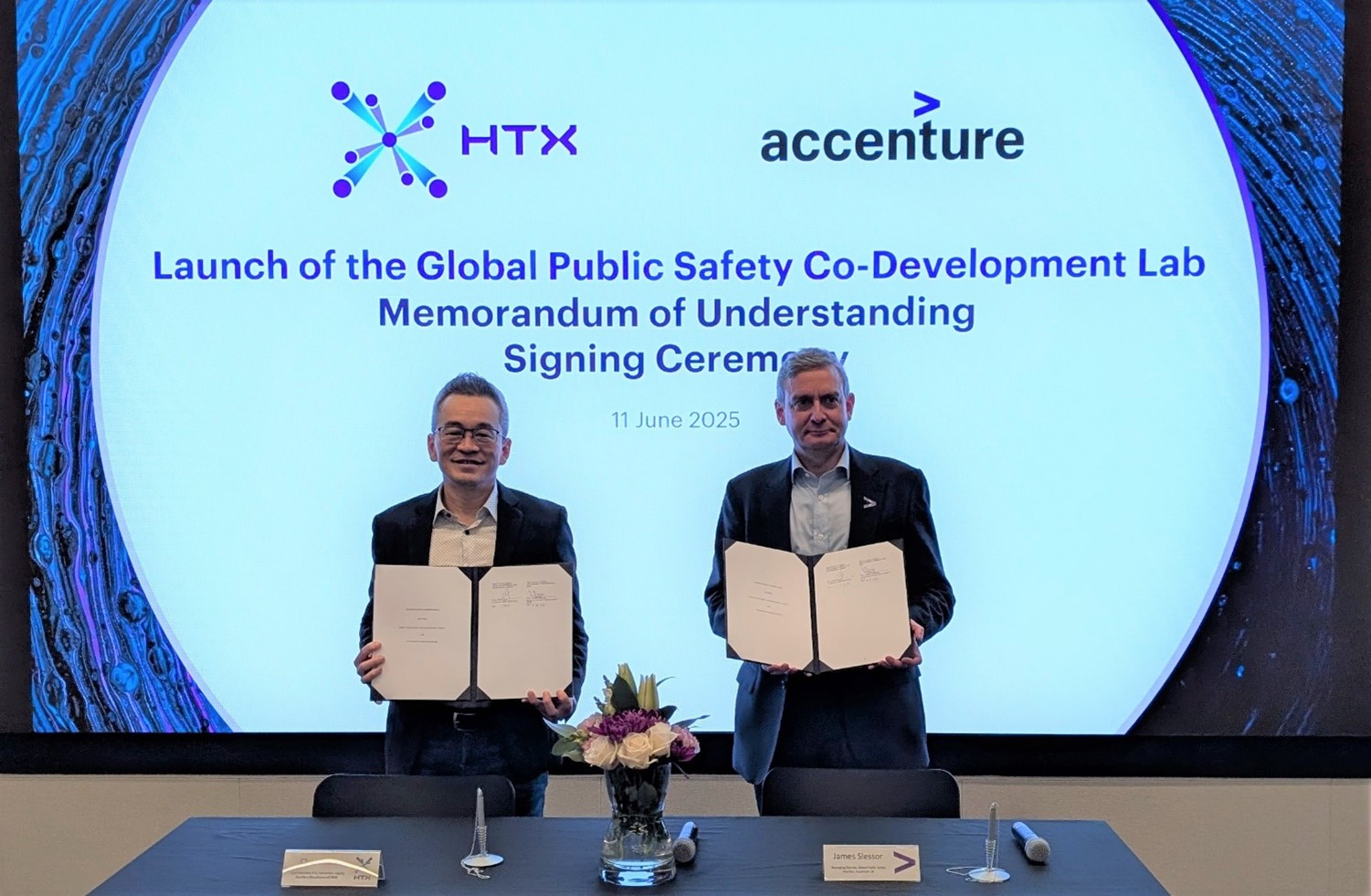 Two men standing and holding signed MOUs