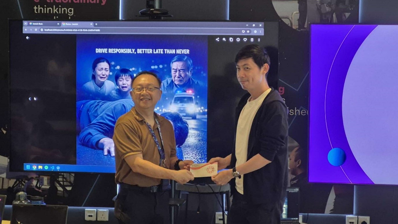 A person receiving a small prize from another person standing in front of a TV screen.