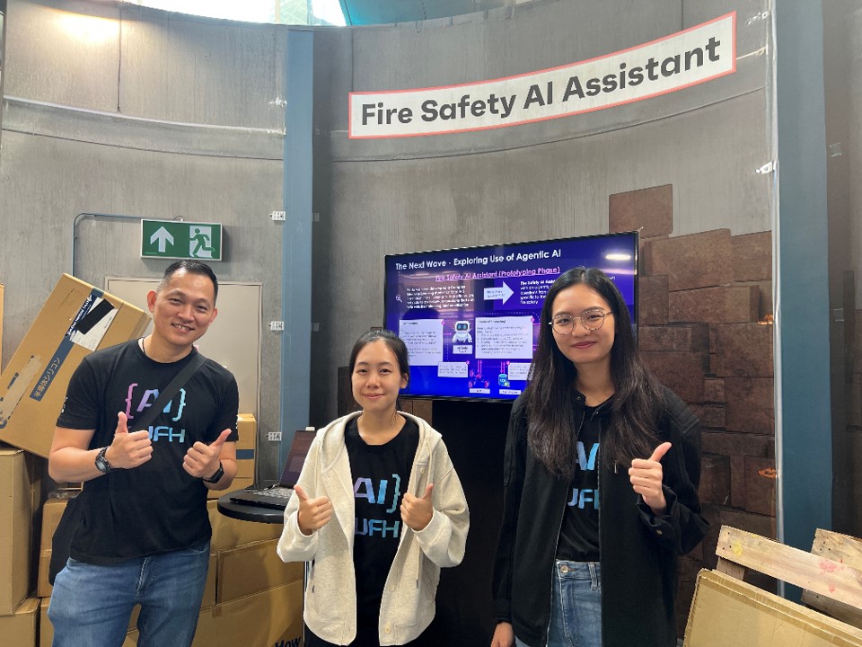 One man and two women posing at Fire Safety AI Assistant booth.