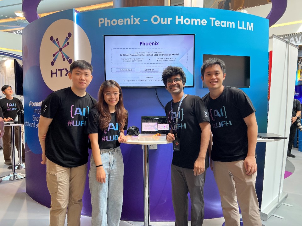 Three men and one woman pose at Phoenix - Our Home Team LLM booth.