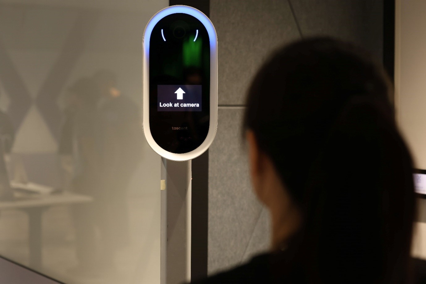 A person looking at a machine which has the words "Look at camera" on it.