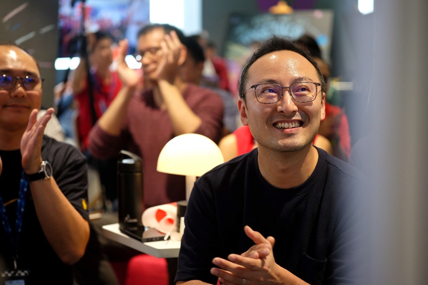 A man in glasses smiles and claps.