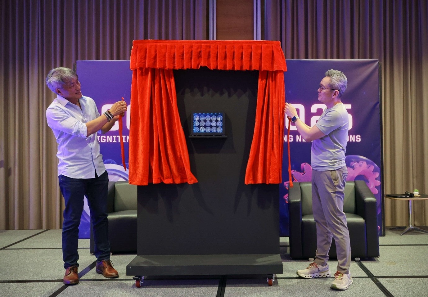 Two men on stage unveiling display