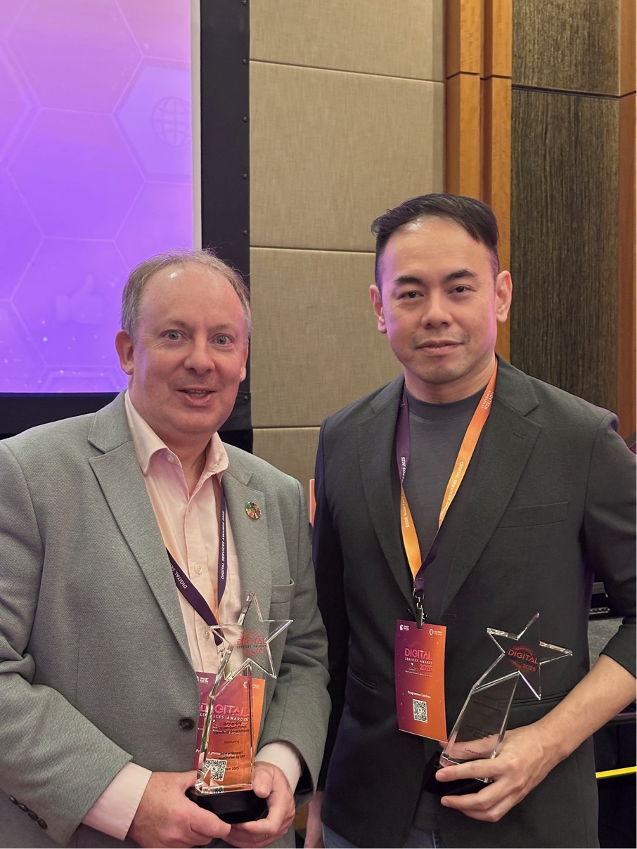 Two men standing with trophies.