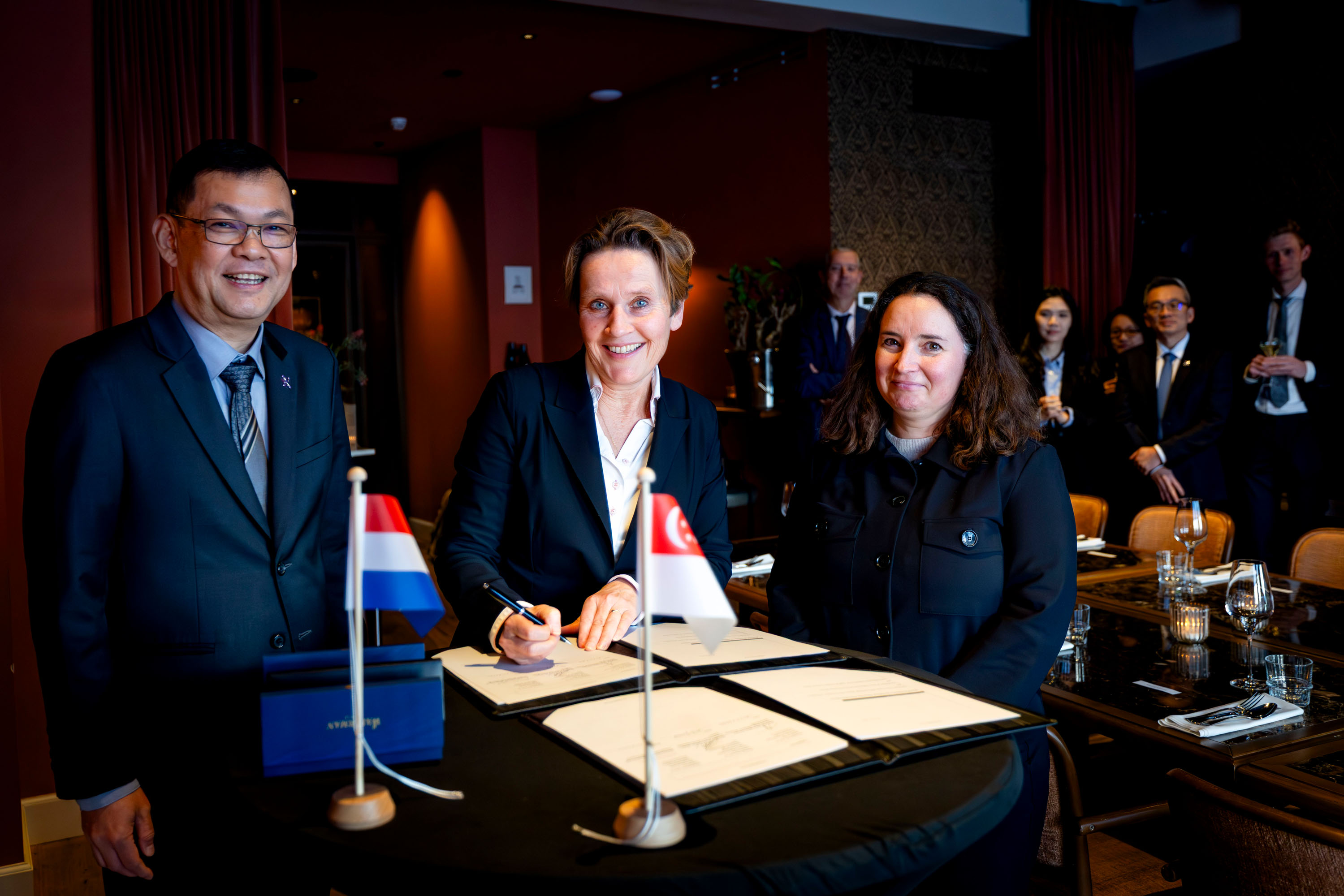 A man and two women standing at a table signing a document.
