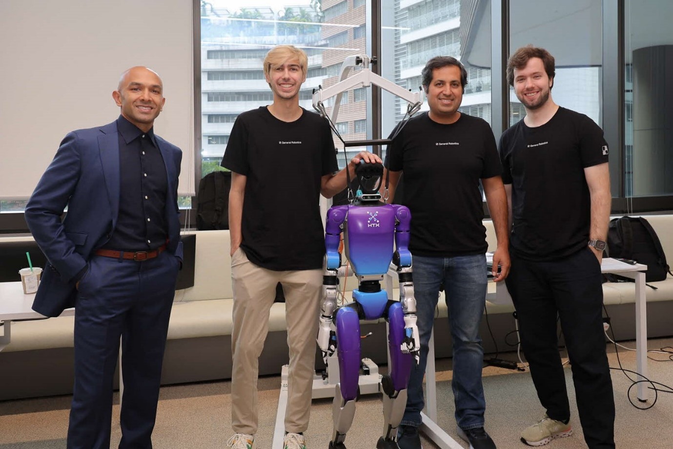 A group of four men standing next to a humanoid robot.