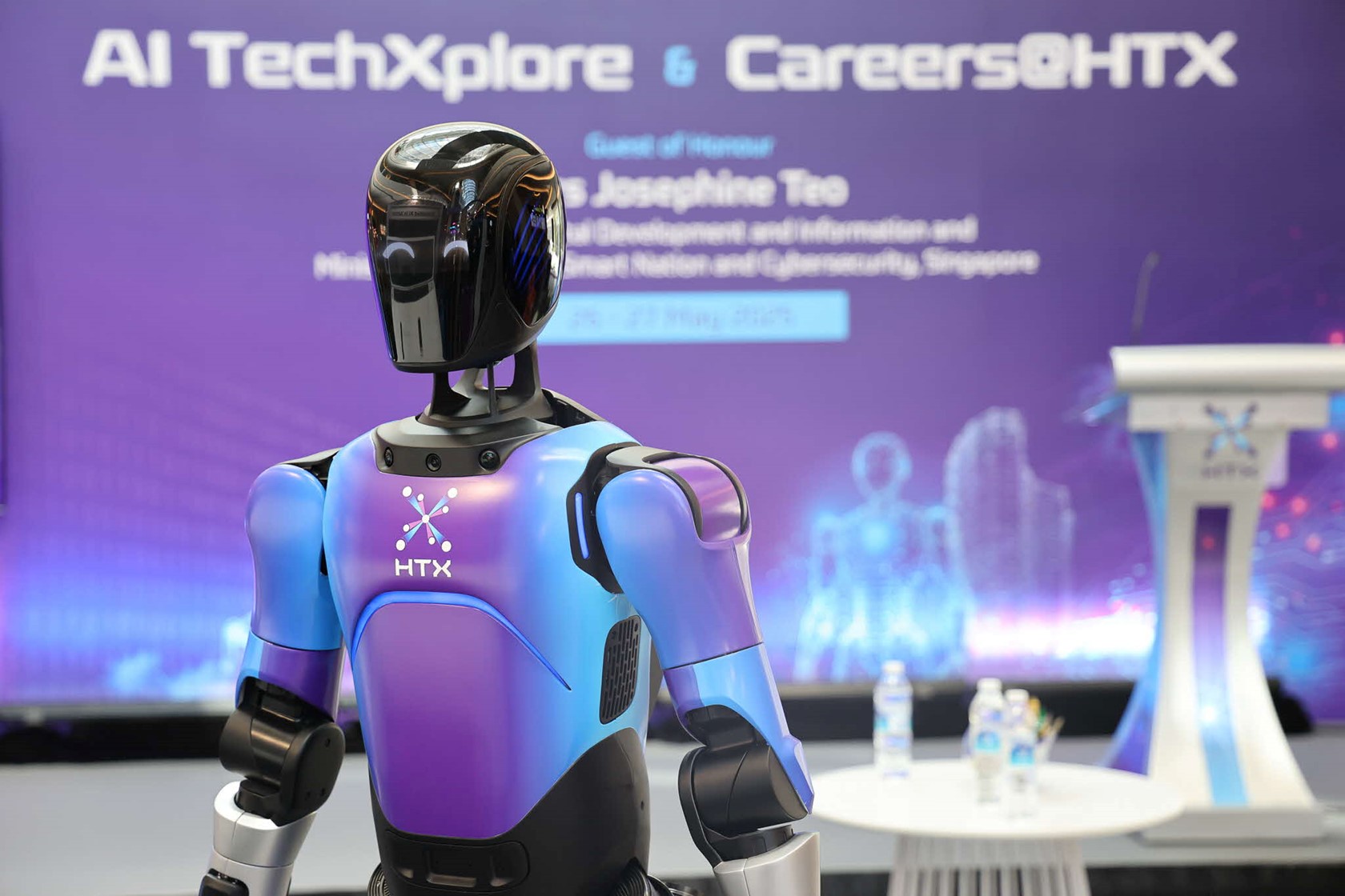 A robot standing in front of the event backdrop.