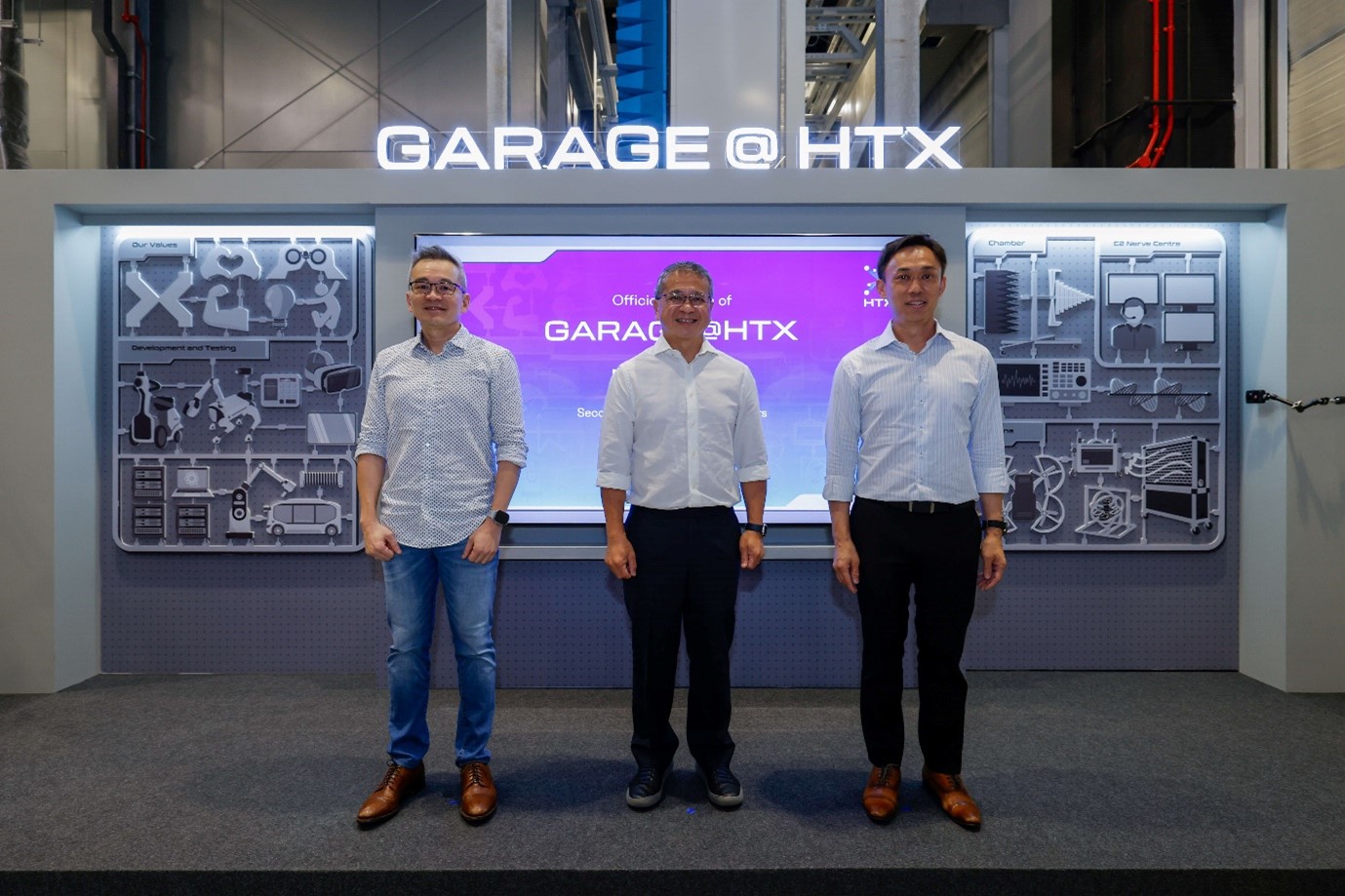 A group of three men standing in front of a stage backdrop.