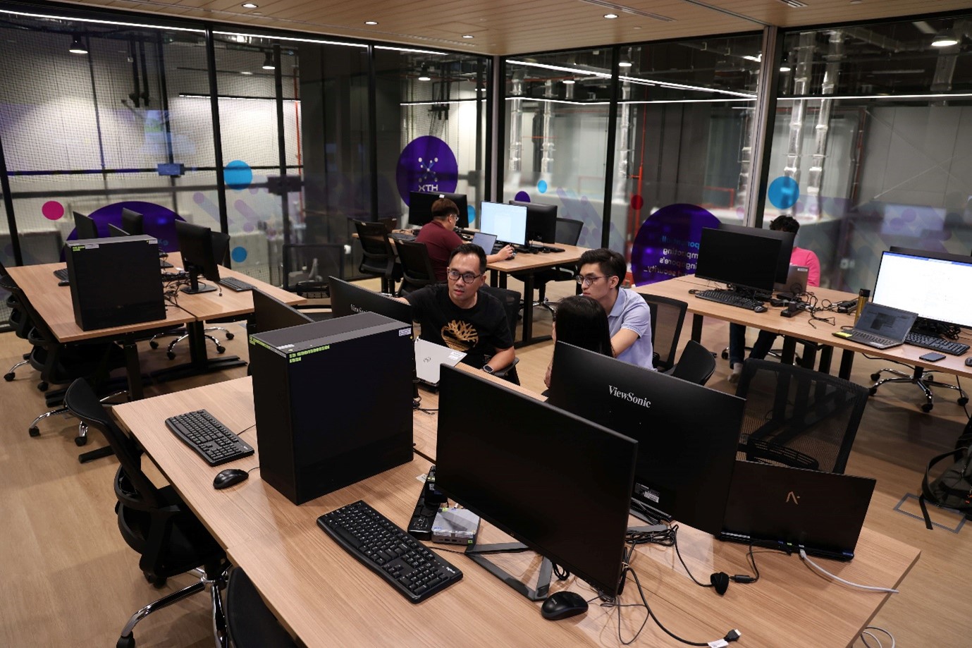 A room full of computers and screens and people working on them.