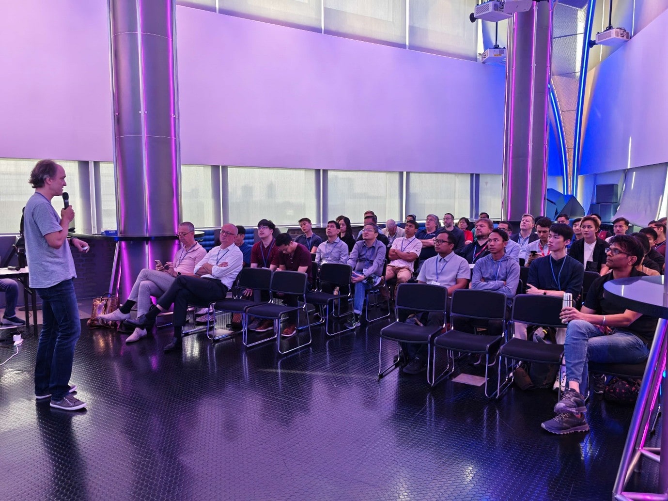 A group of people sitting in chairs listening to a standing man.
