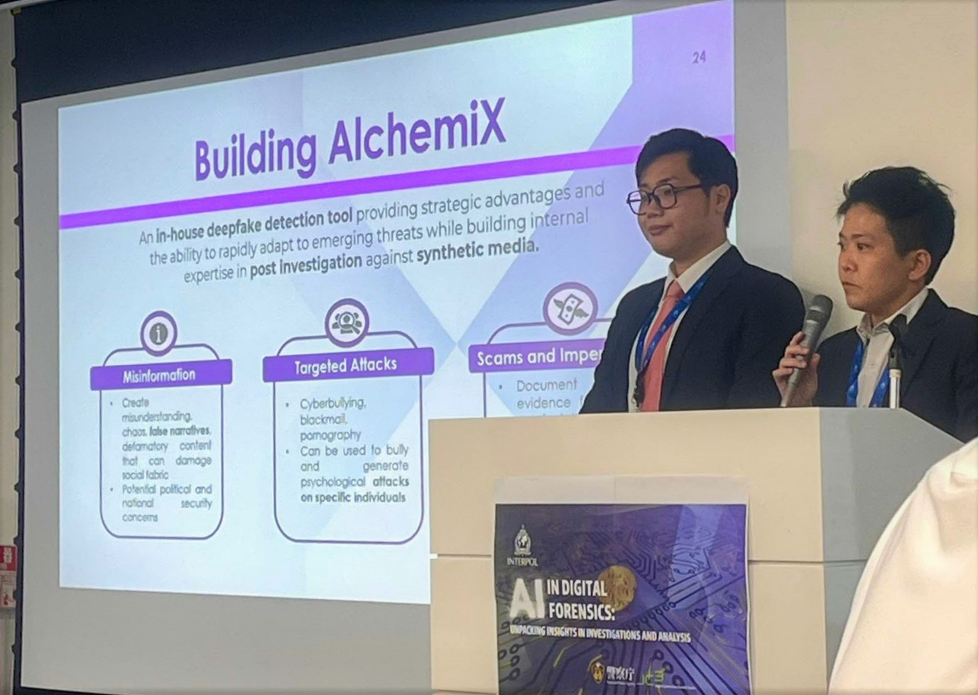 Two persons at the podium, one holding a microphone.