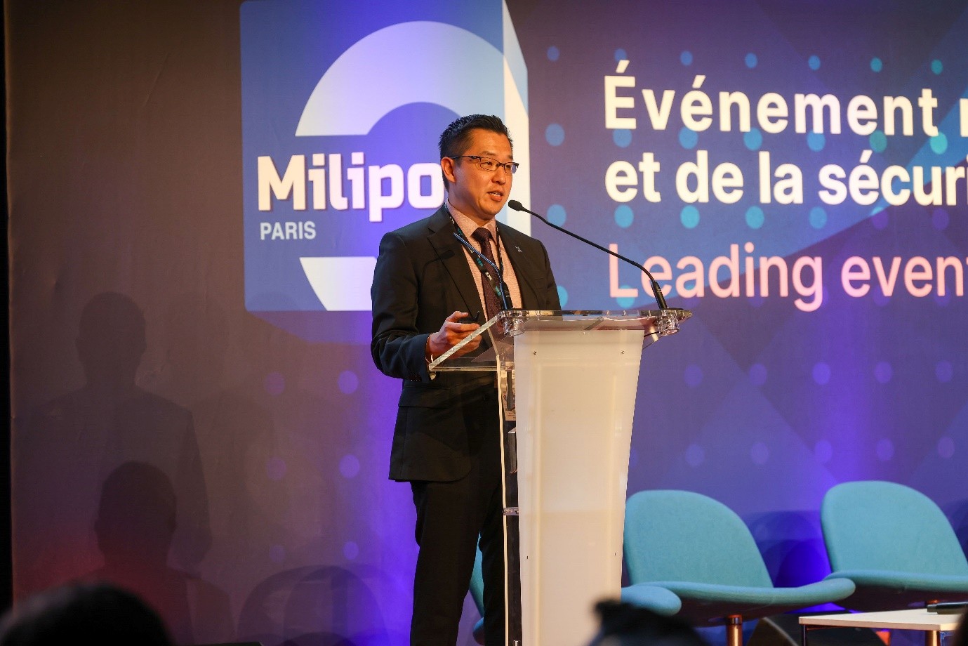 A man in a suit speaks at a podium.