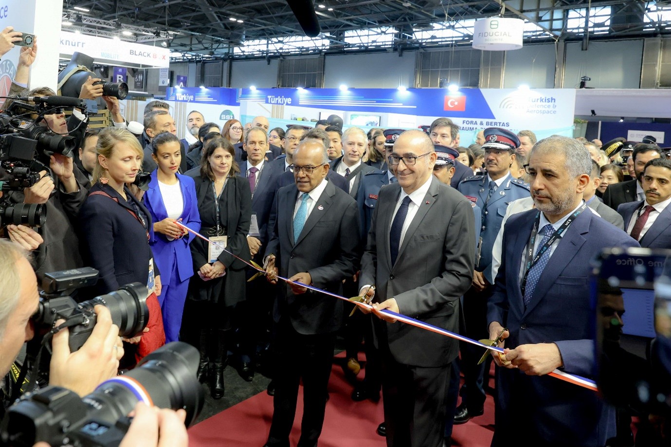 Three people cutting a ribbon.