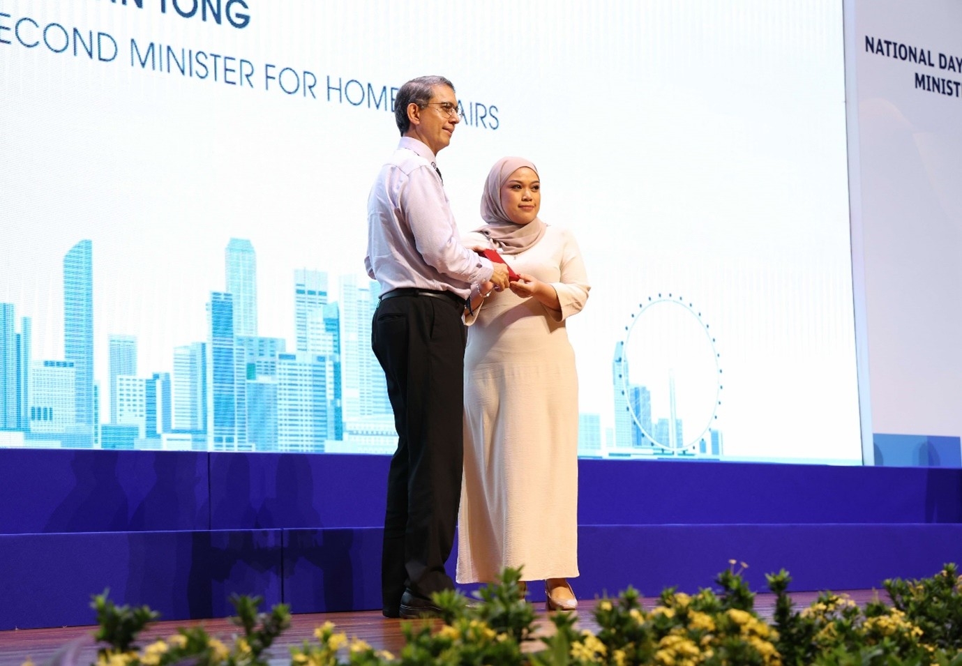 A man presenting an award to a woman on stage.