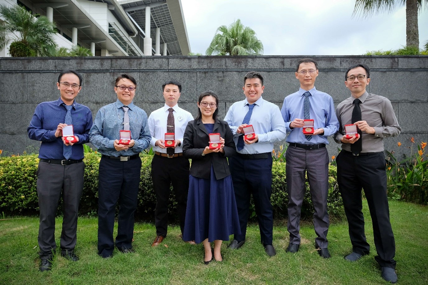 The group of seven people holding their award in a red box.