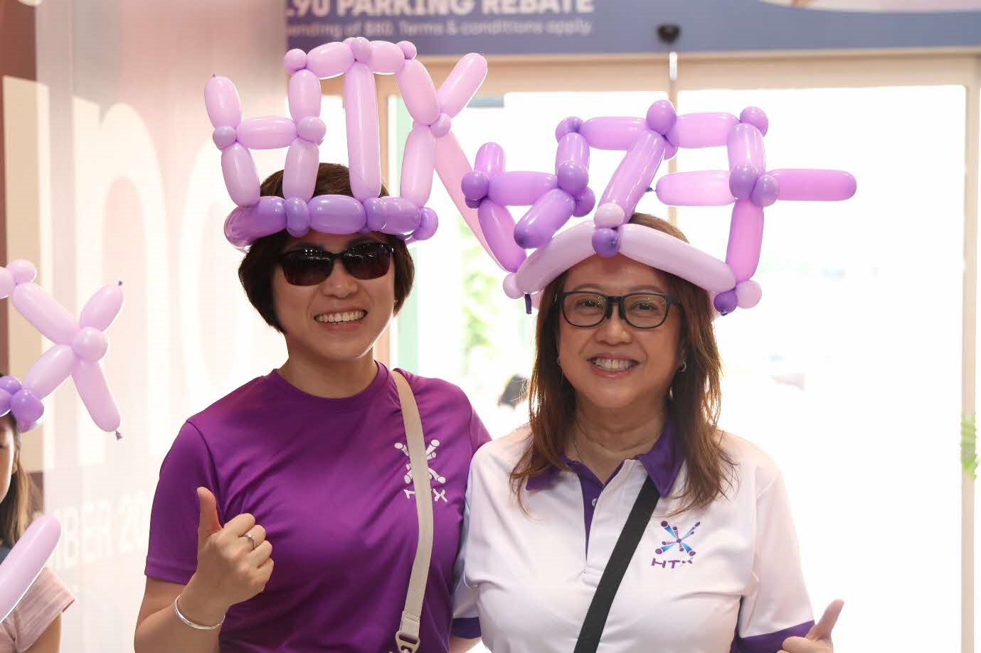 Two women wearing balloons on their heads.
