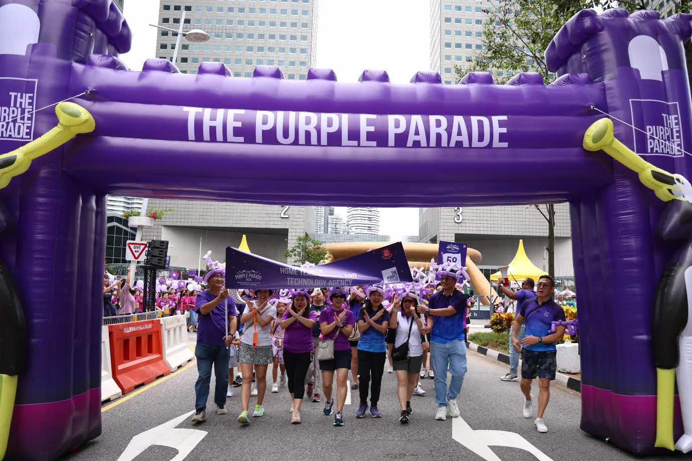 A group of people walking under a purple archway.