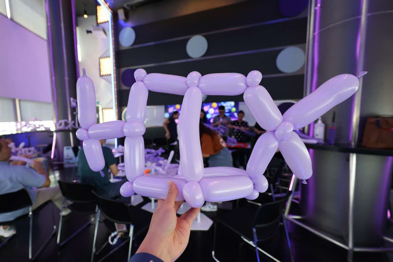 A person holding a balloon shaped like the letters "HTX".