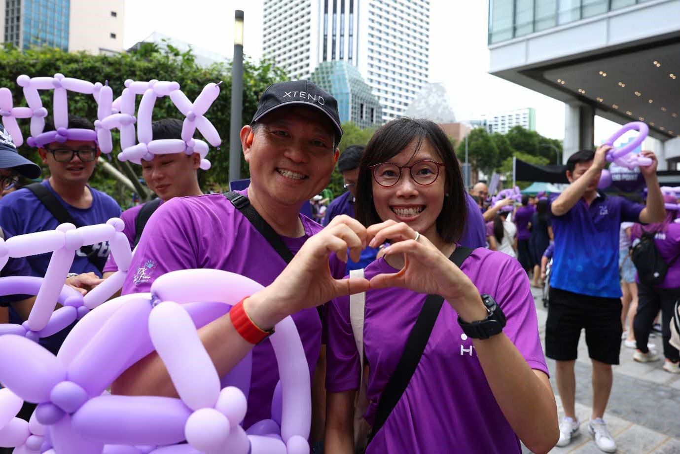 A male and female jointly make a heart shape with their hands.