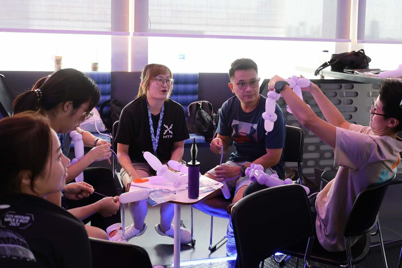 A group of people sitting around a table and holding balloons.