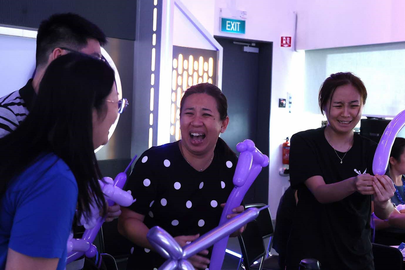 A group of people laughing while holding balloons.