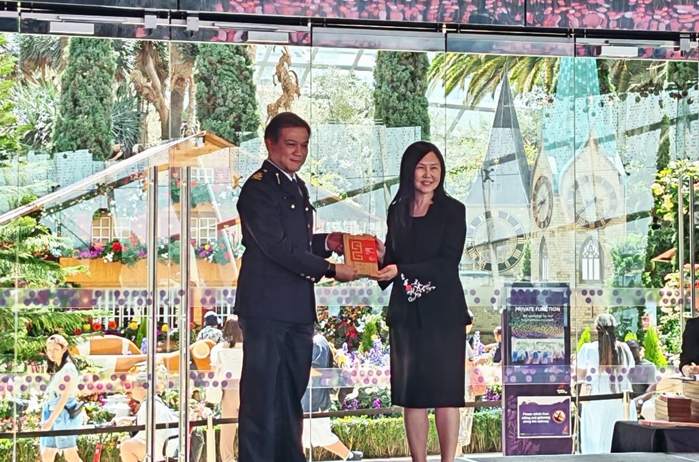 Two people on a stage, with a man in a formal uniform presenting an award to a woman.