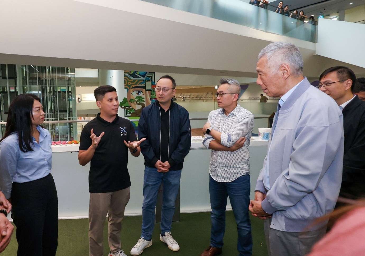 A group of people standing in a circle. One person is gesturing while the others look at him.