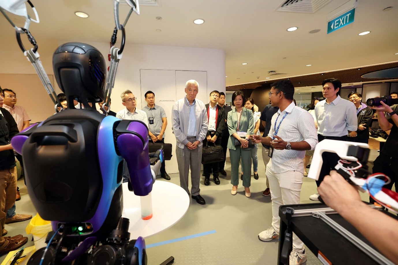 A group of people standing around a humanoid robot.