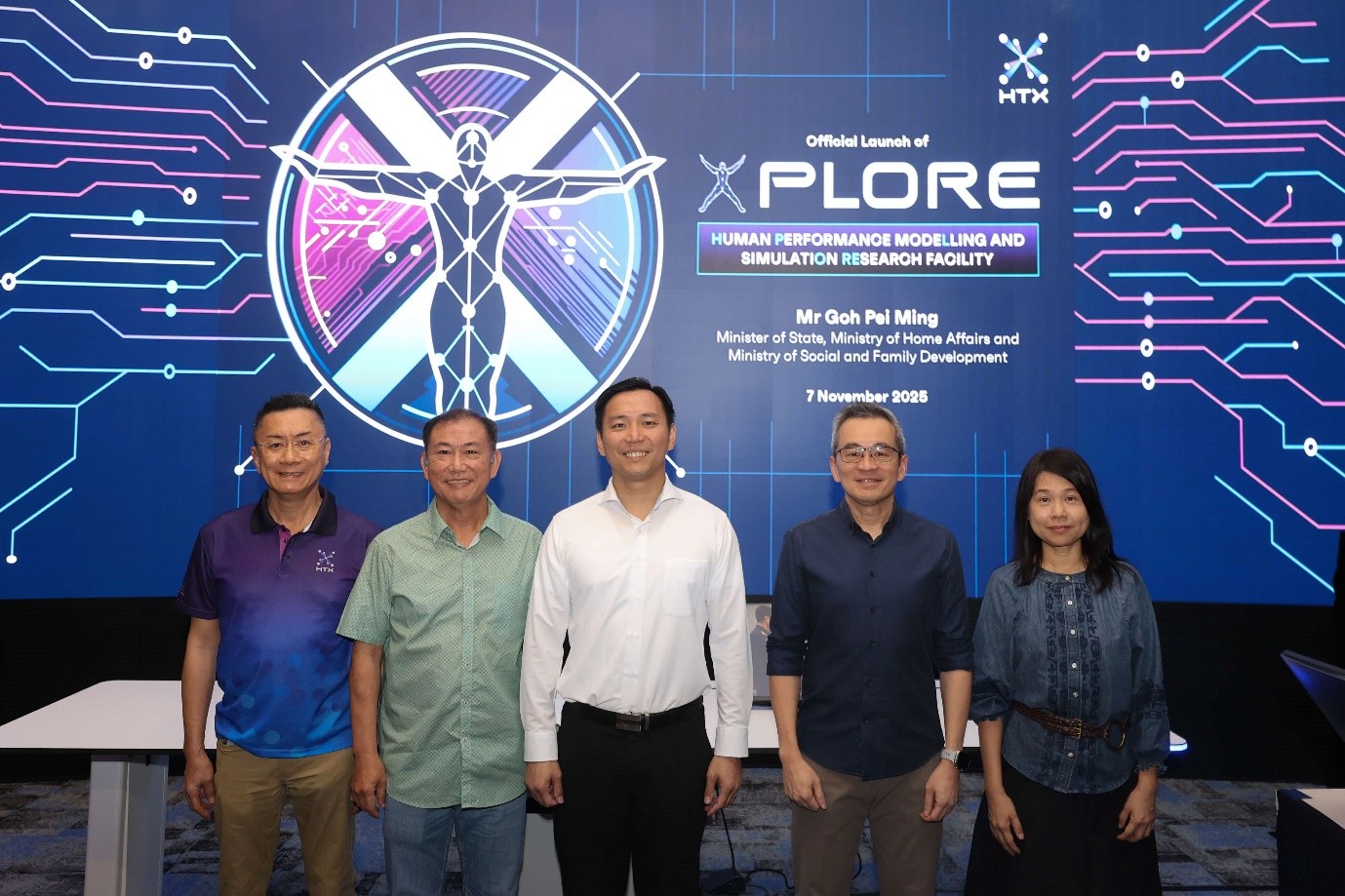 Five people, including MOS Goh, pose for a photo in front of a screen announcing the "Official Launch of XPLORE Human Performance Modelling and Simulation Research Facility."
