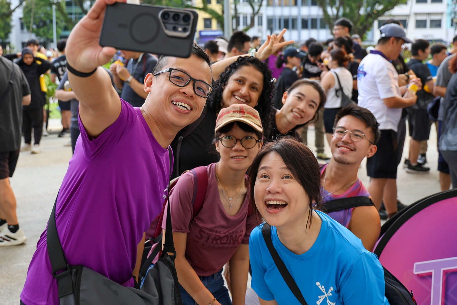 Six smiling adults taking a group selfie.