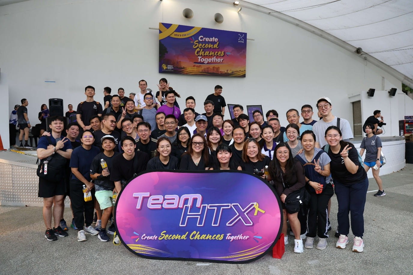 Large group posing behind a purple "Team HTX" sign.