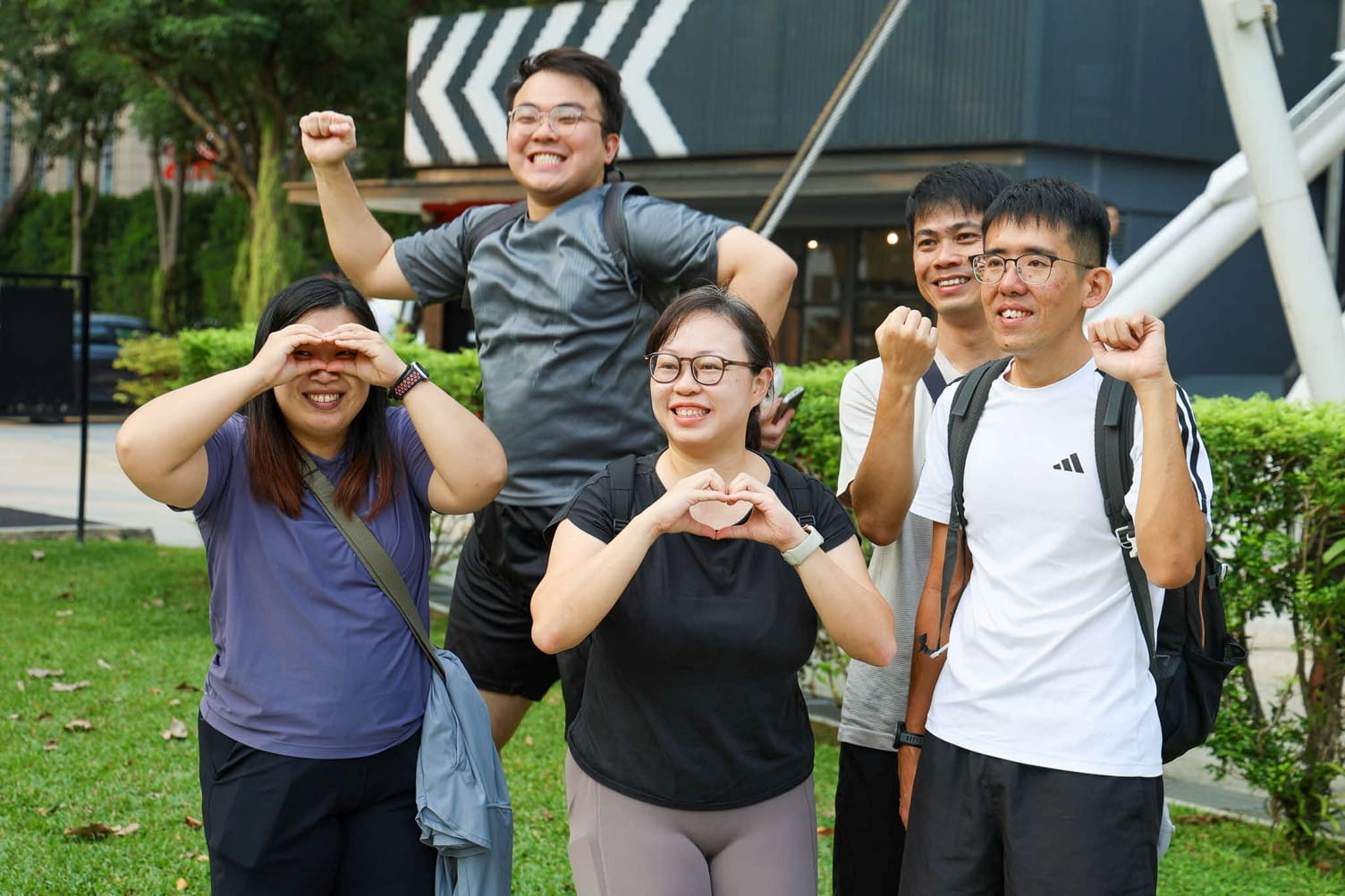 Five smiling adults posing outdoors.