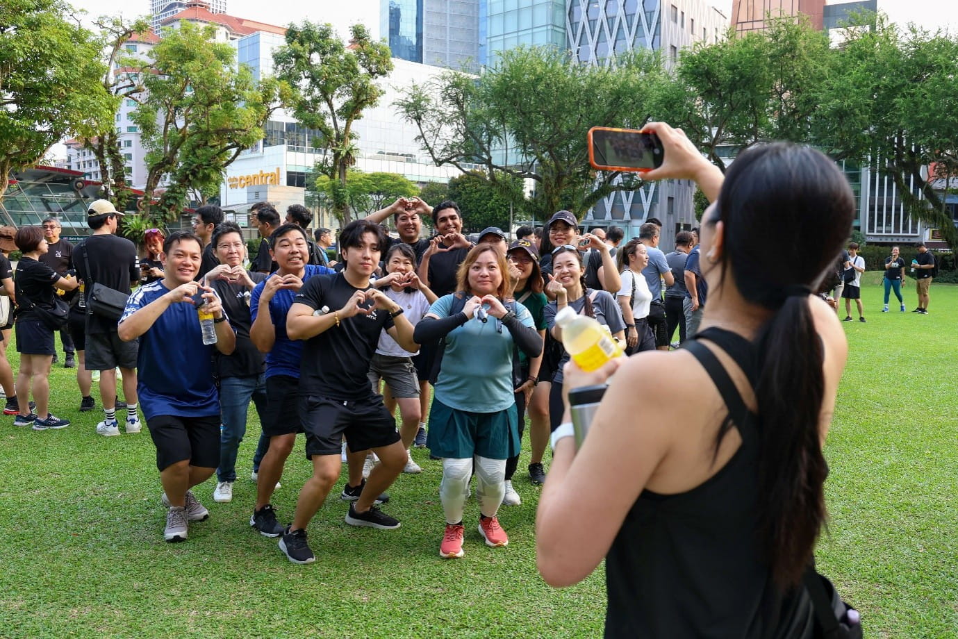 Group posing for a photo outdoors, while a lady takes their photo.
