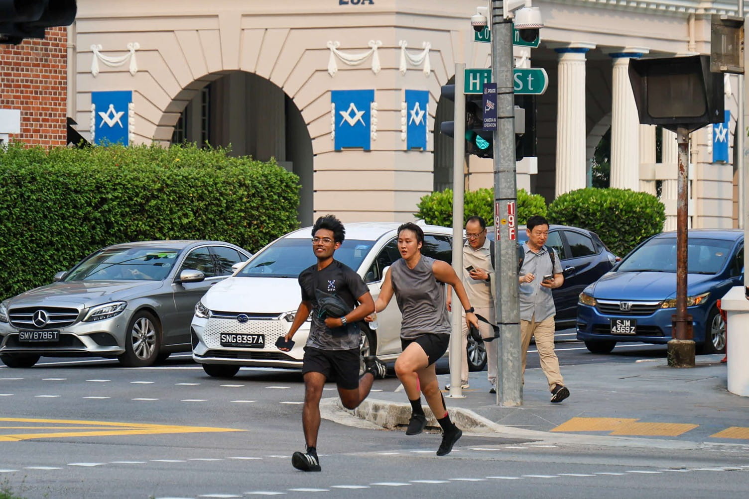 Two runners cross a street.