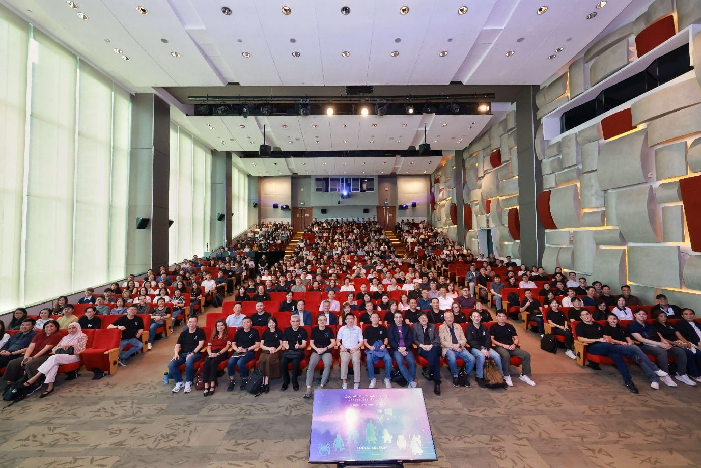 Large audience in a modern auditorium.