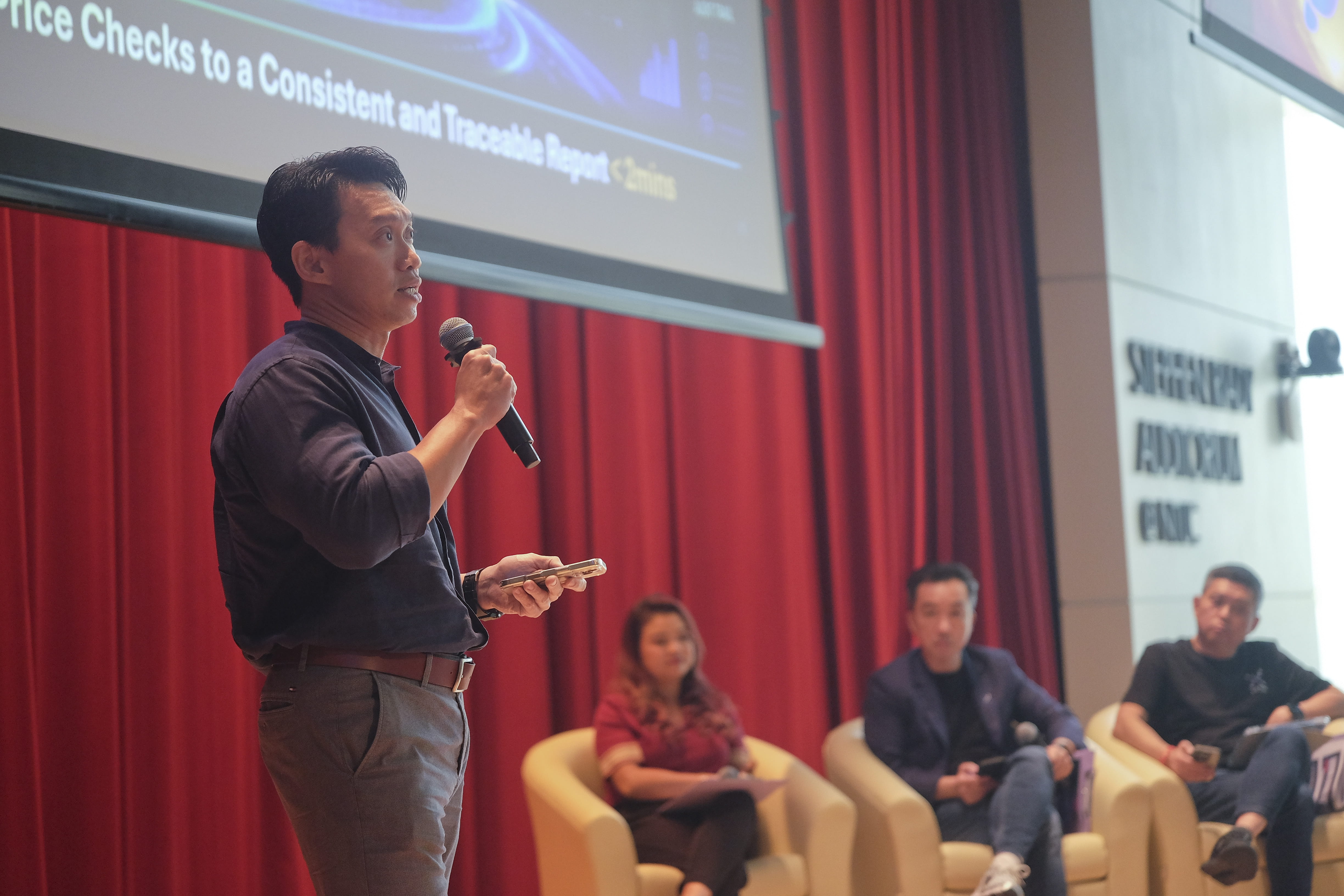 Presenter holding a microphone during a session on stage.