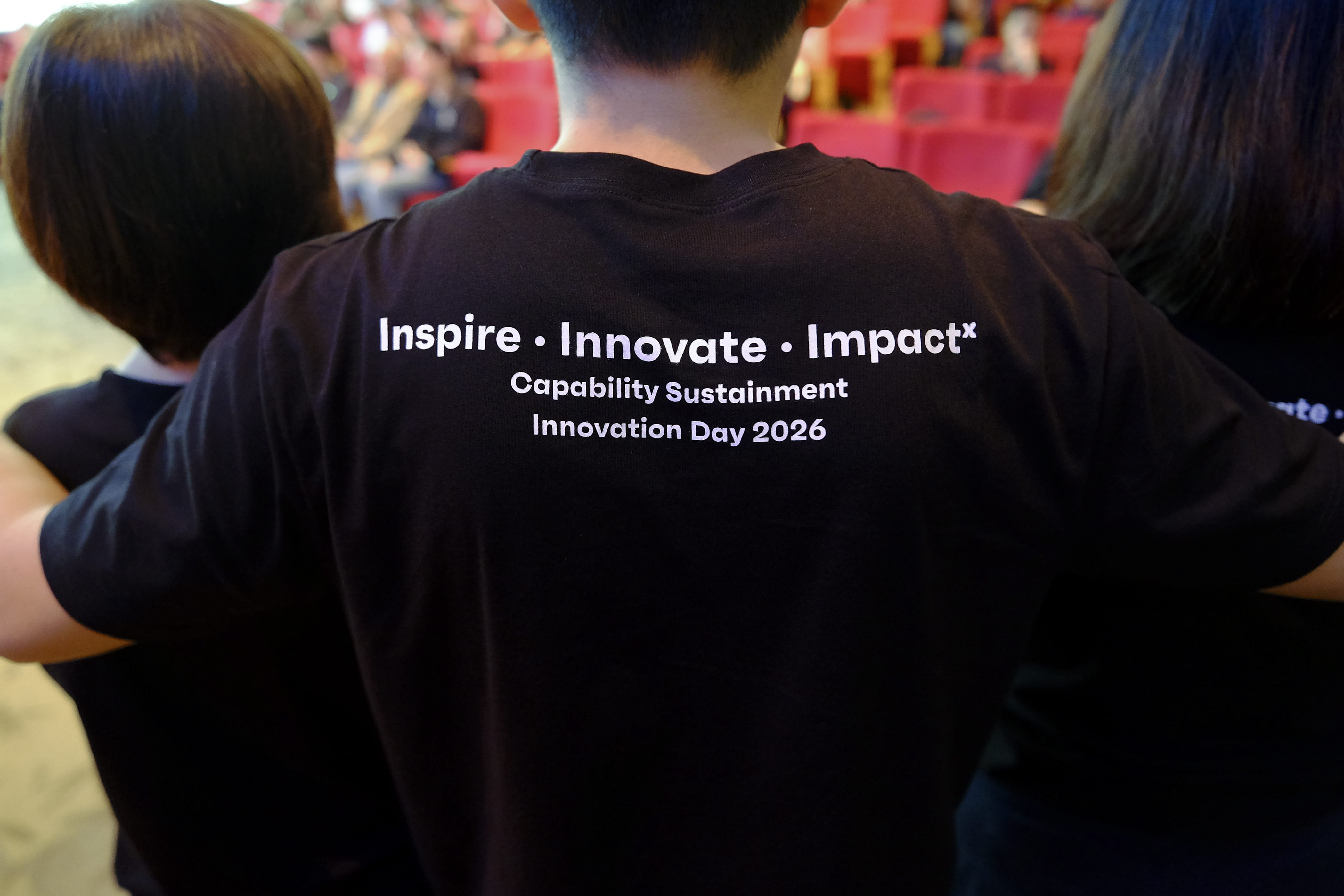Back of a black shirt reads "Inspire • Innovate • Impact”, “Capability Sustainment Innovation Day 2026” highlighting the event theme.