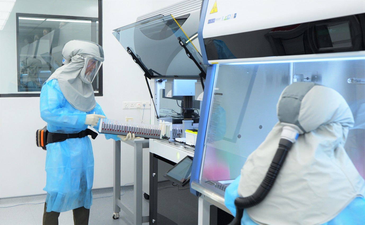 Two scientists in protective suits working in a lab.