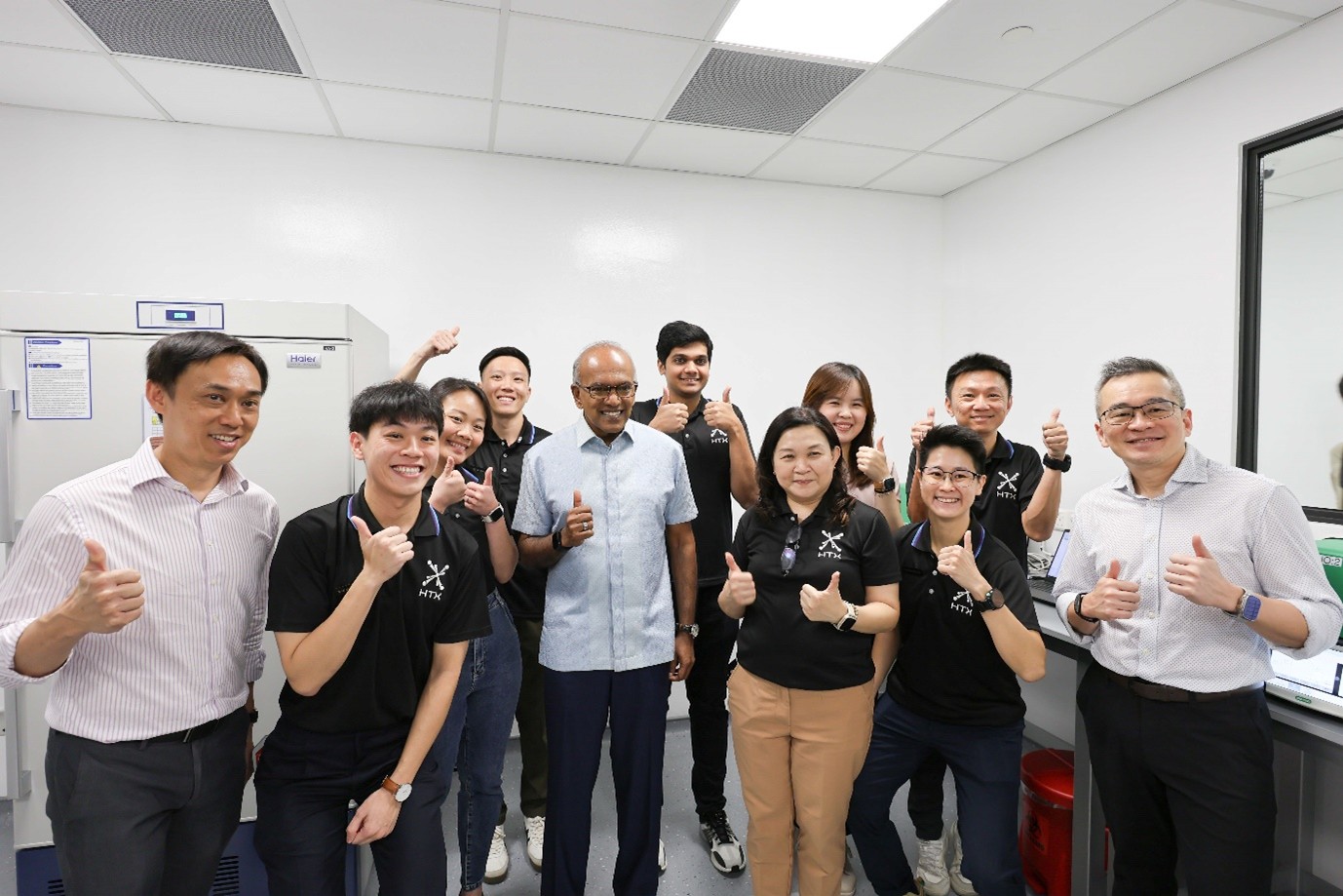 Team posing in a lab with thumbs up.