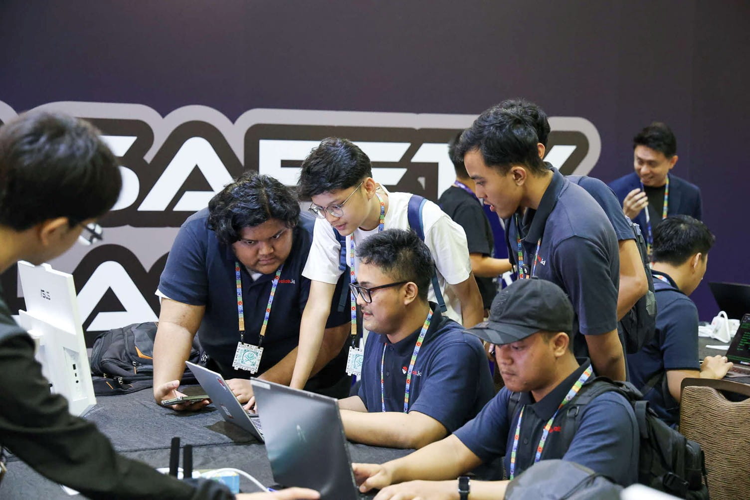Group of people gathered around laptops.