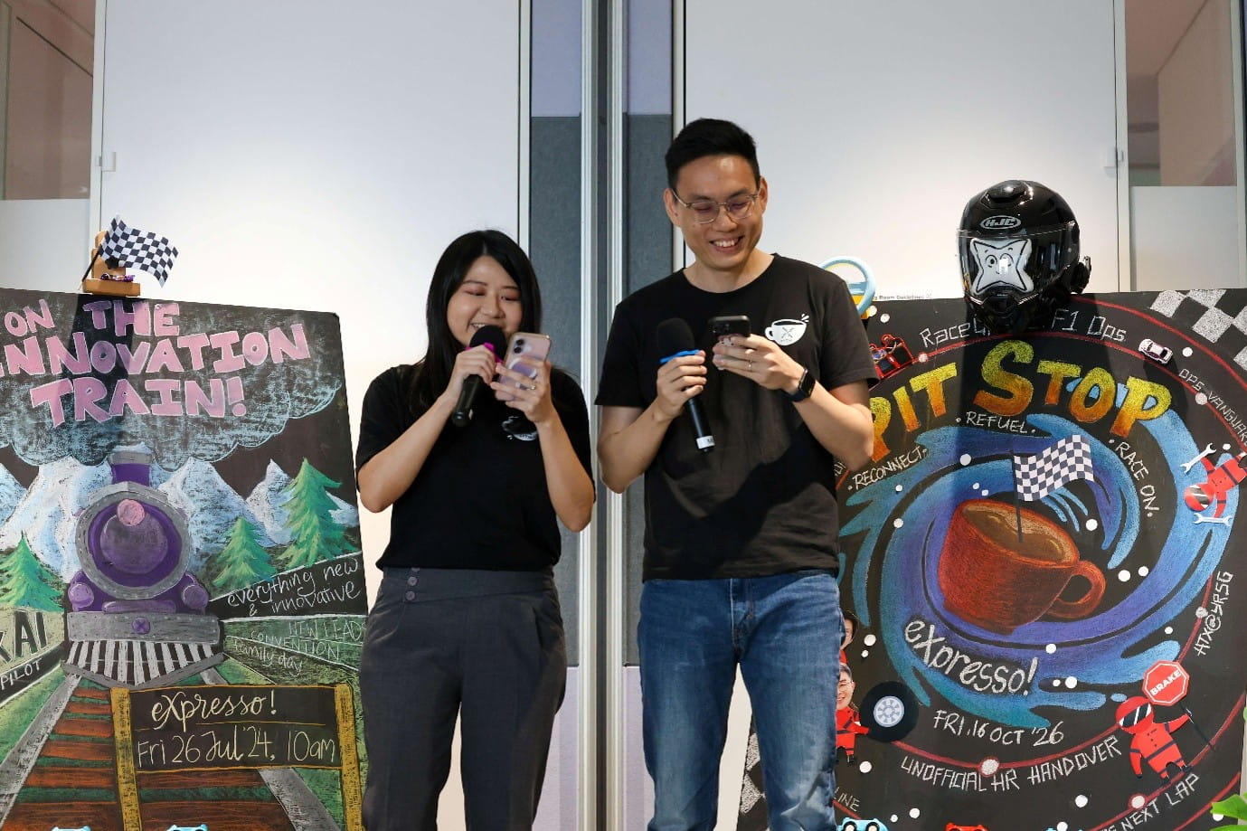 Two presenters holding microphones and phones.