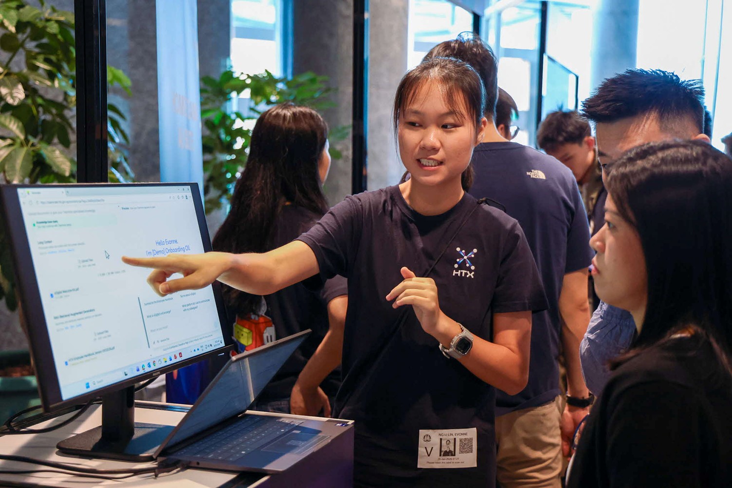 A woman in an HTX shirt pointing at a computer screen.