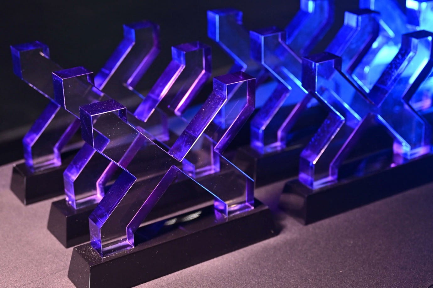 Translucent trophies shaped like stylised "X" letters arranged in rows.