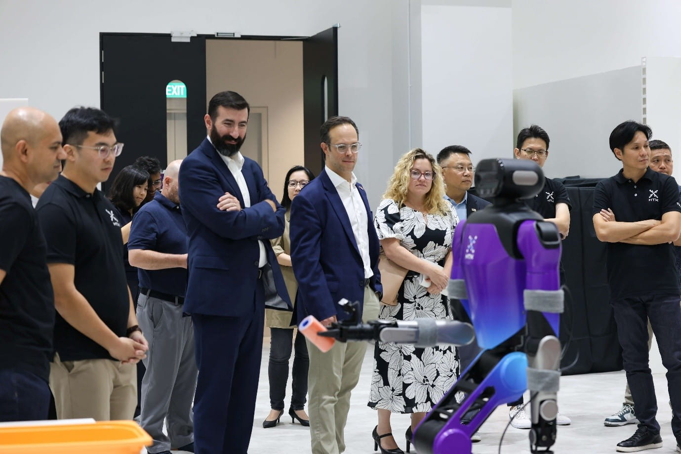 A humanoid robot demonstration, with the robot facing an audience inside a facility.