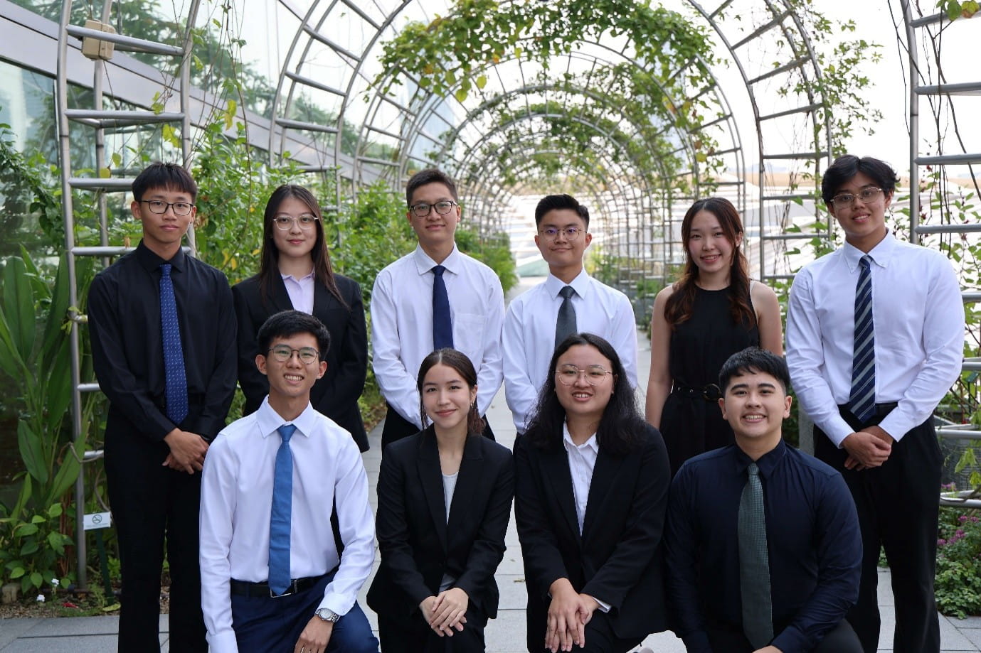 Group of ten young adults dressed in formal attire posing.