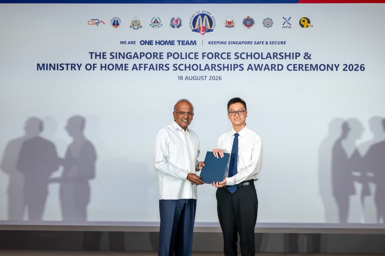 A young man receives his scholarship award from a man on stage.