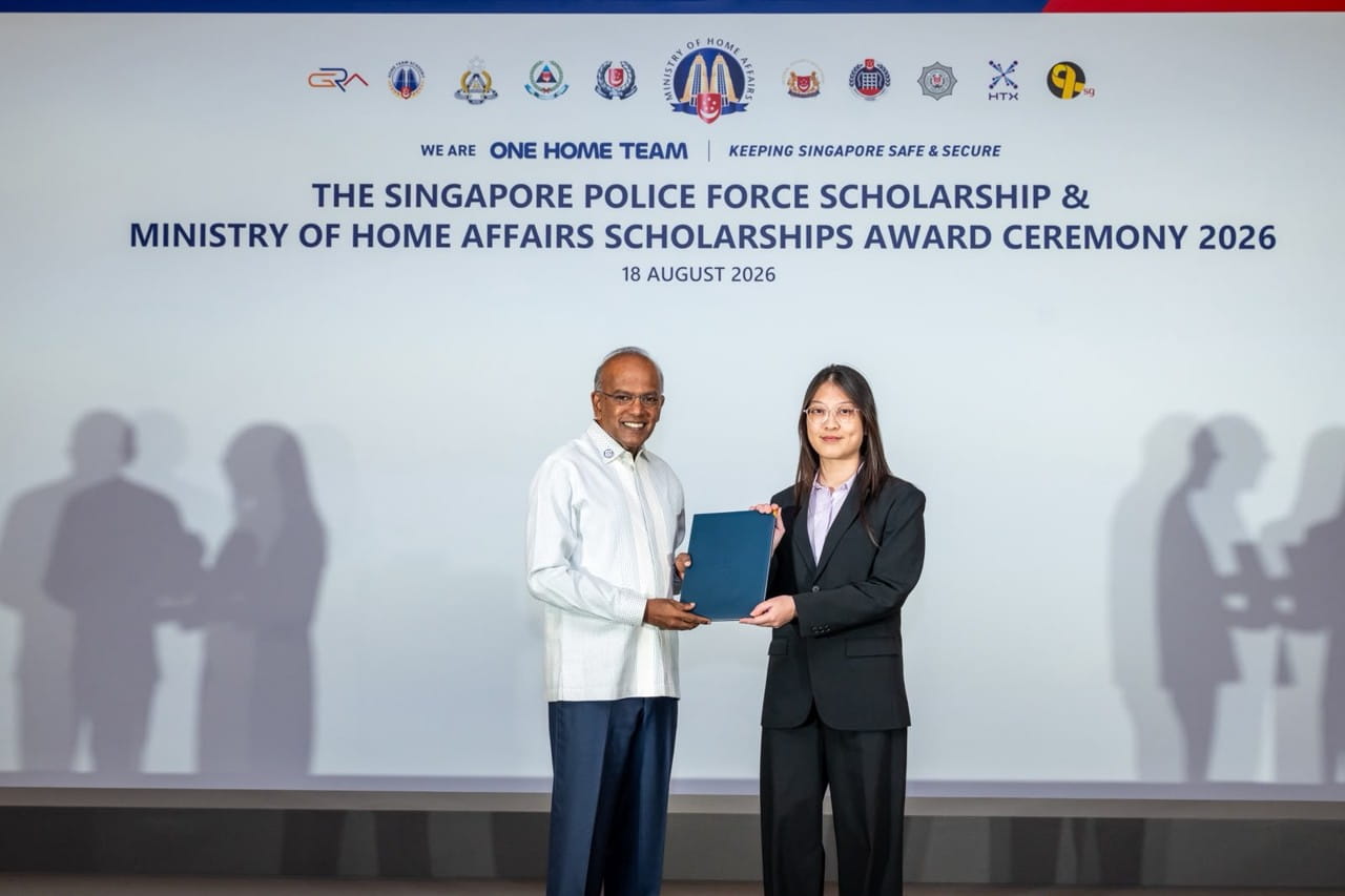 A young woman receives her scholarship award from a man on stage.