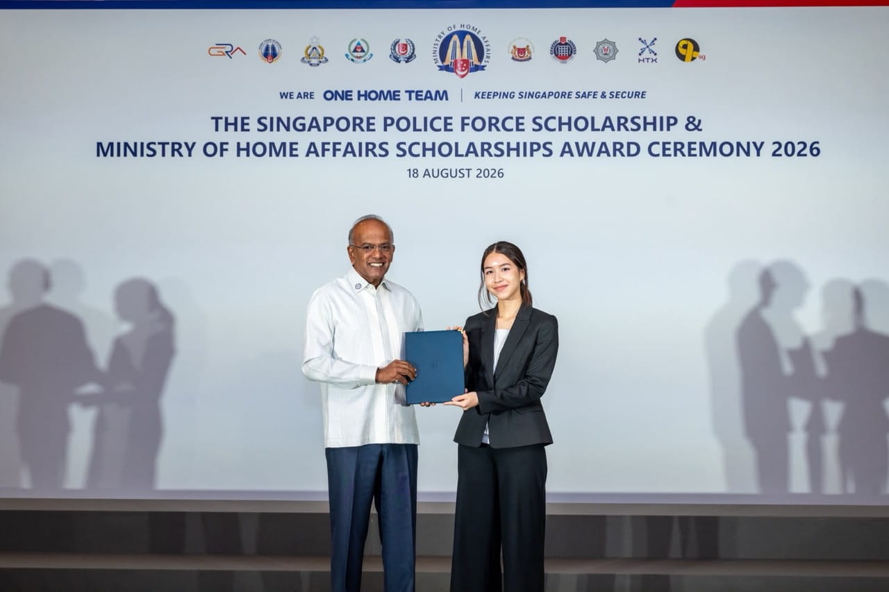 A young woman receives her scholarship award from a man on stage.