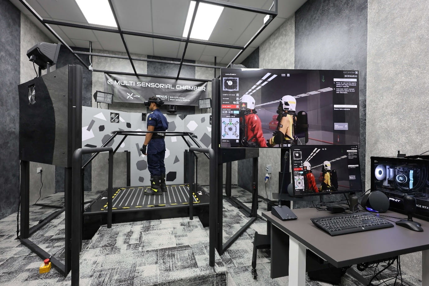 A person wearing a VR headset stands on a treadmill in a room with computer screens.